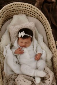Adelaide siblings looking at their new baby sister in a mosses basket.