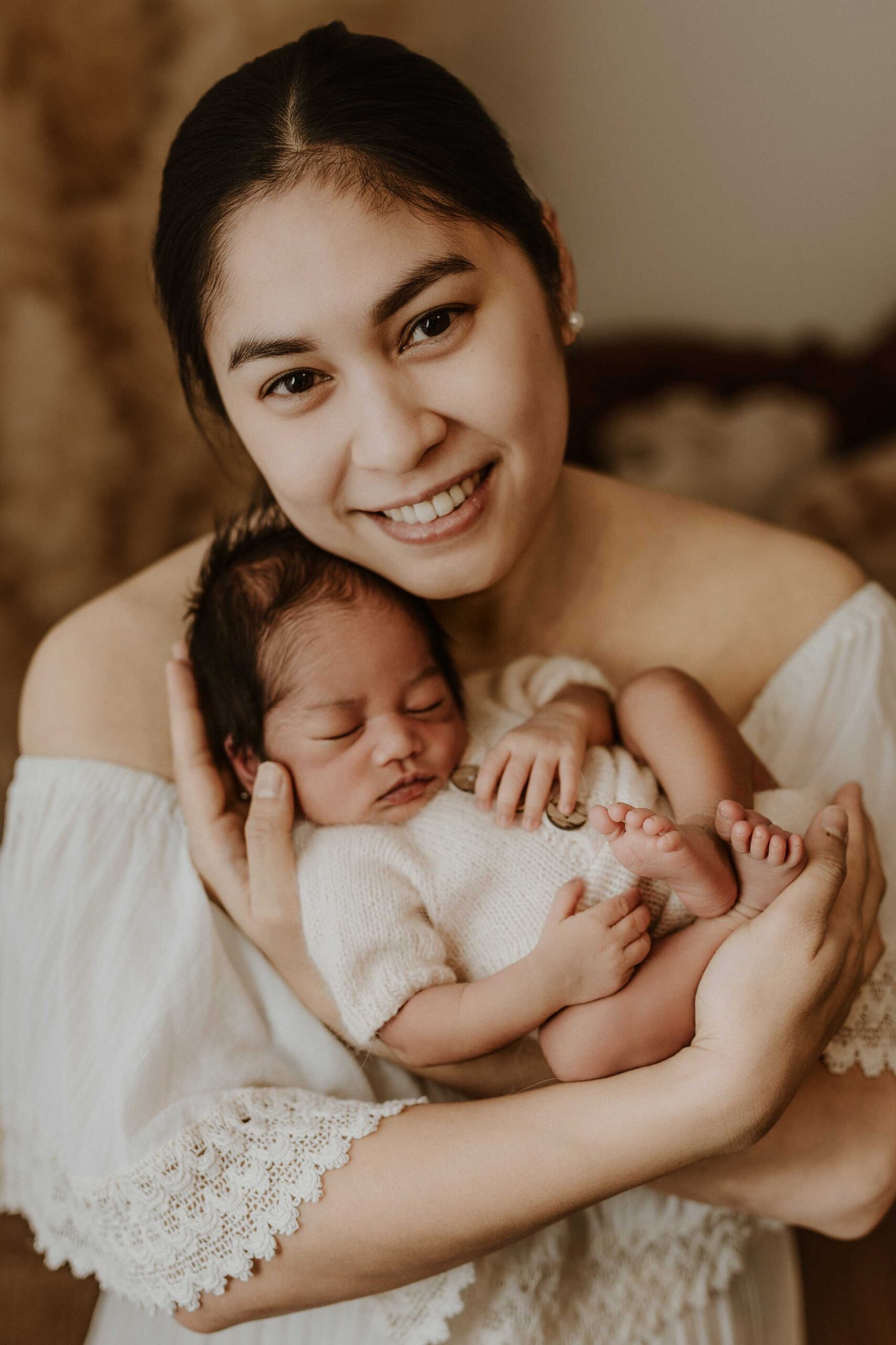 An Adelaide mum who is smiling and holding her newborn baby on her chest.